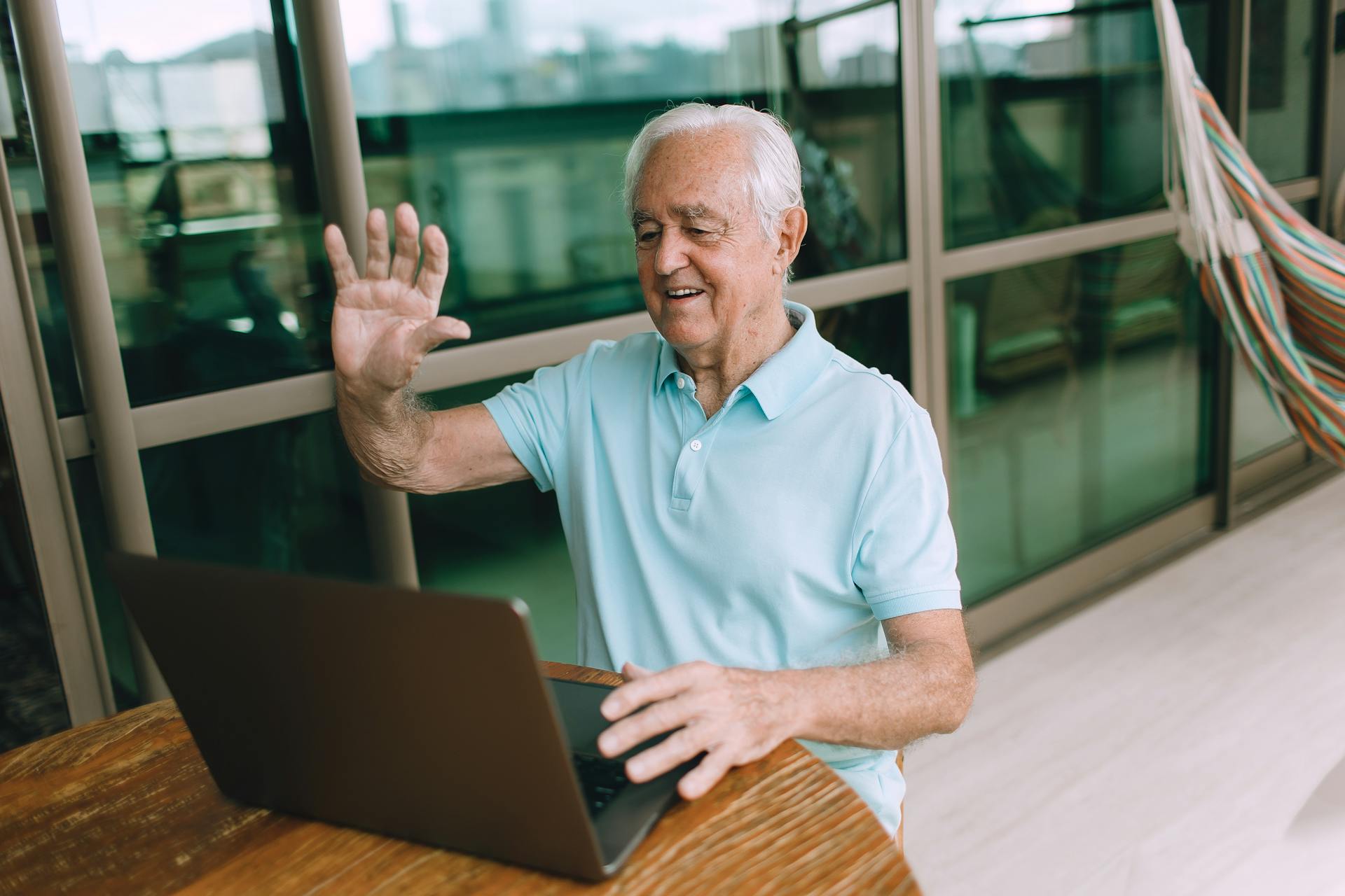 Robert, 78, senior man waving at his laptop during a Social Circle video call session