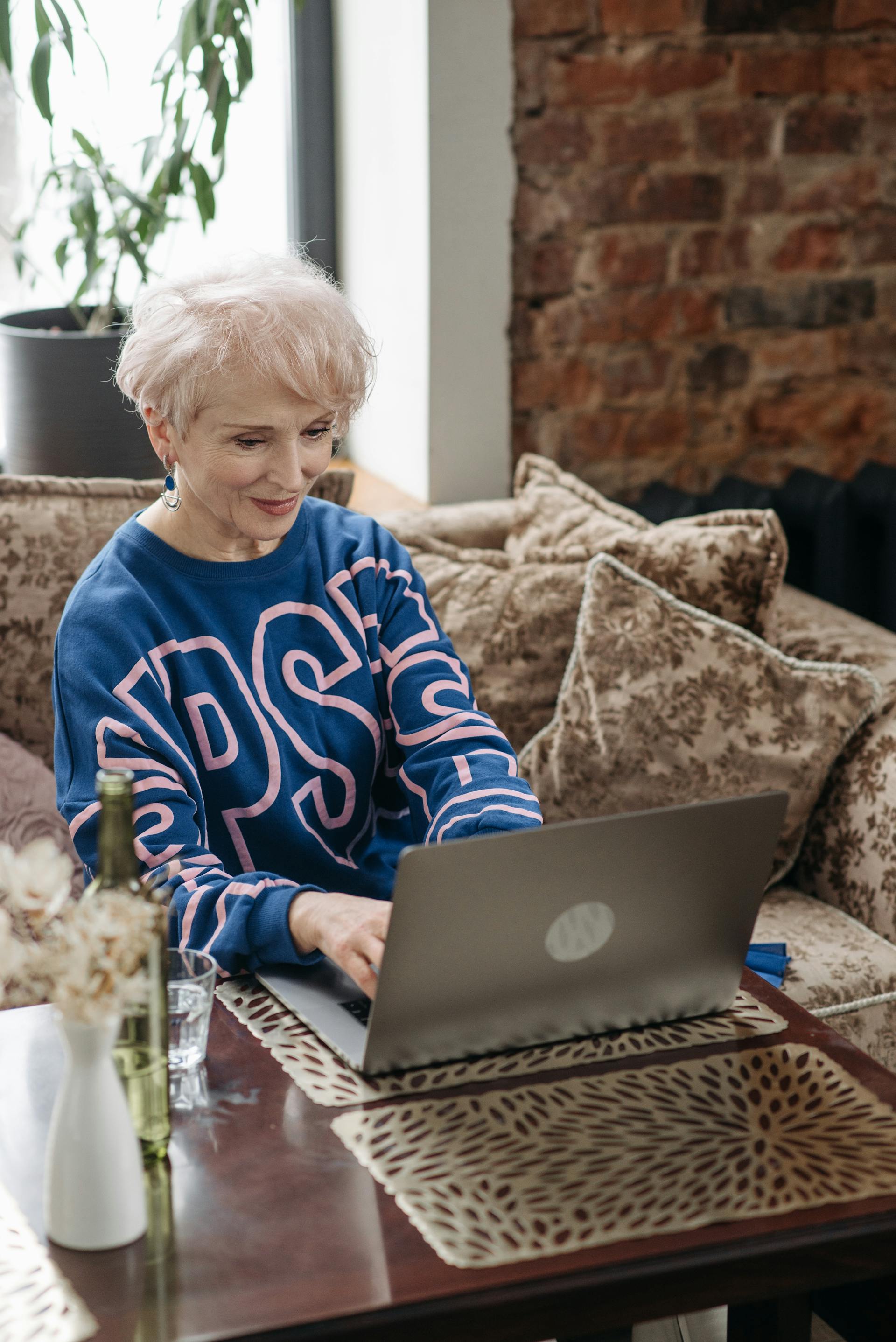 Carol, 71, senior woman with white hair on her laptop joining her Social Circle from home